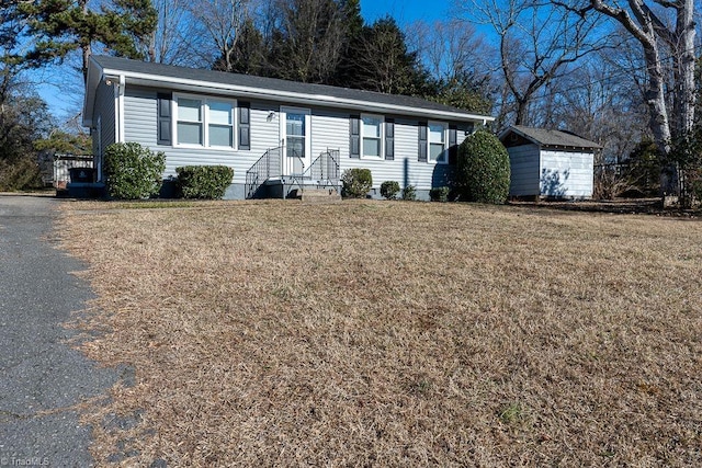 ranch-style house featuring a storage shed and a front lawn