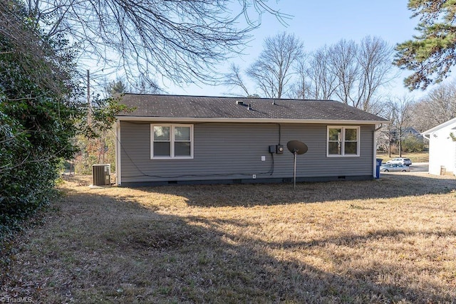 rear view of house with central AC unit and a lawn