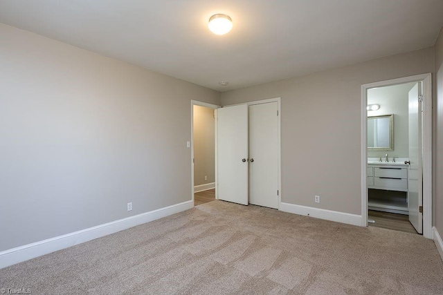 unfurnished bedroom with ensuite bathroom, sink, light carpet, and a closet