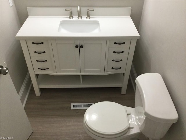 bathroom with vanity, toilet, and hardwood / wood-style floors