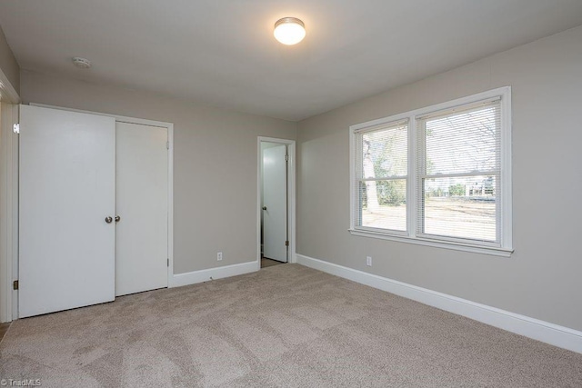 unfurnished bedroom featuring light carpet and a closet