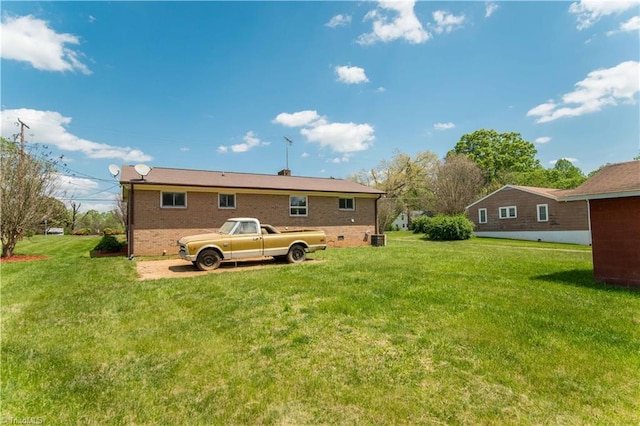 rear view of property with a lawn, brick siding, and cooling unit