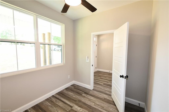 empty room with baseboards, ceiling fan, and dark wood-style floors
