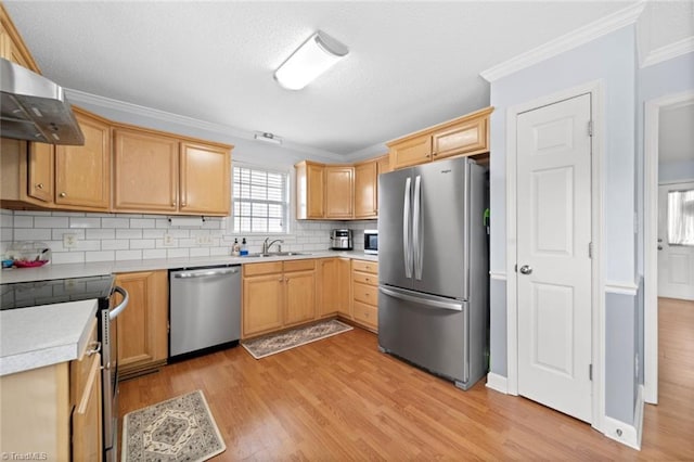 kitchen featuring light wood-style flooring, stainless steel appliances, crown molding, light countertops, and wall chimney range hood