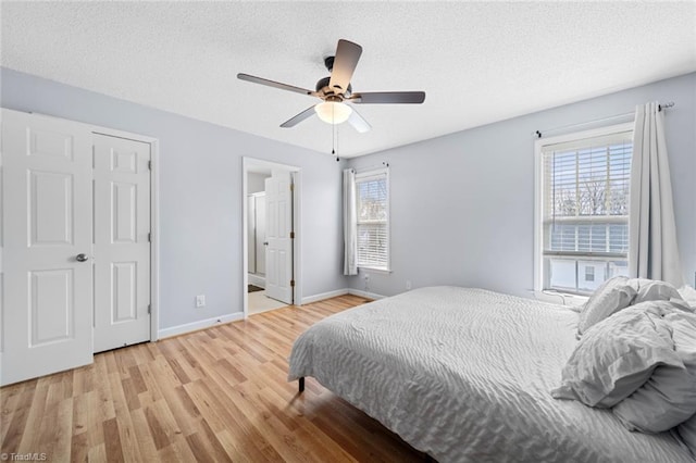 bedroom featuring multiple windows, a textured ceiling, baseboards, and wood finished floors