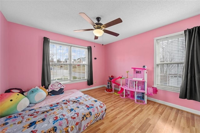 bedroom featuring ceiling fan, a textured ceiling, baseboards, and wood finished floors