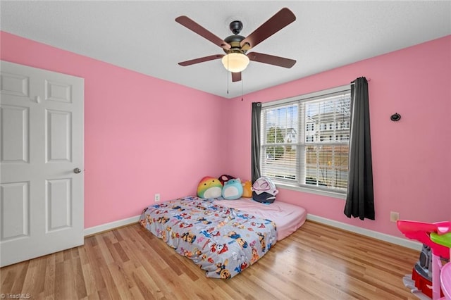 bedroom with ceiling fan, baseboards, and wood finished floors