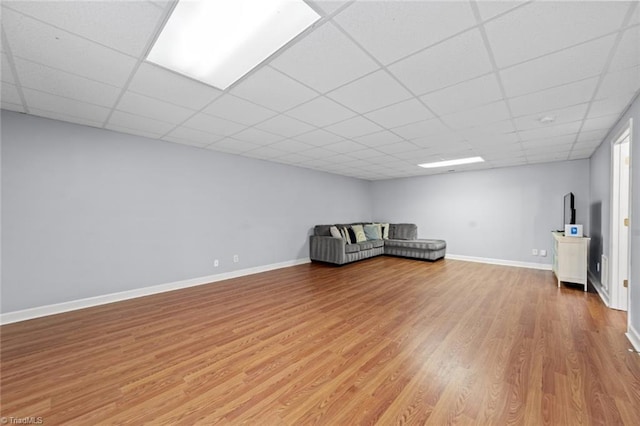 unfurnished room featuring light wood-type flooring, a drop ceiling, and baseboards