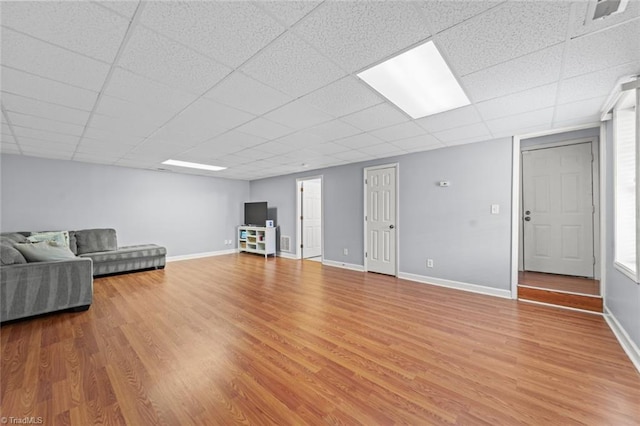 unfurnished living room featuring light wood-type flooring, baseboards, and a drop ceiling