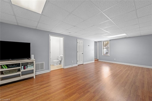 unfurnished living room with visible vents, baseboards, a drop ceiling, and wood finished floors