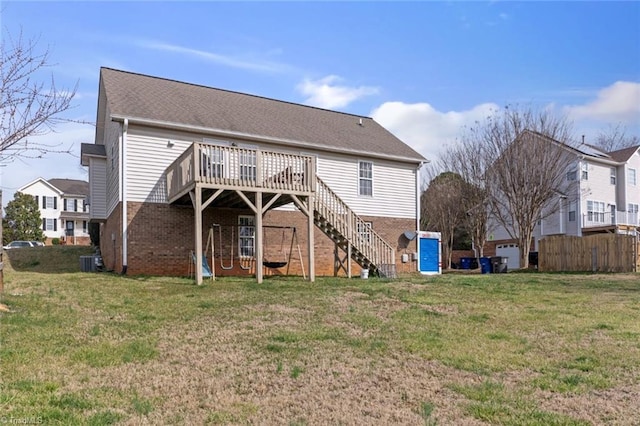 rear view of property with a deck, cooling unit, brick siding, stairway, and a lawn