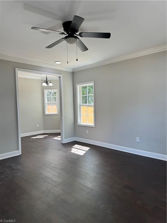 empty room featuring dark wood-type flooring, crown molding, and ceiling fan with notable chandelier