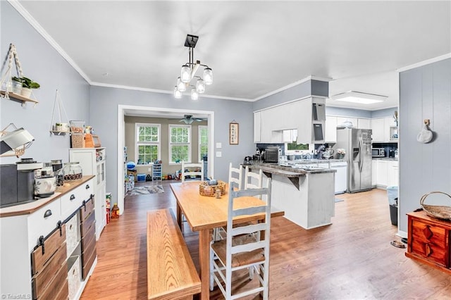 dining area featuring light hardwood / wood-style flooring, ceiling fan with notable chandelier, and crown molding