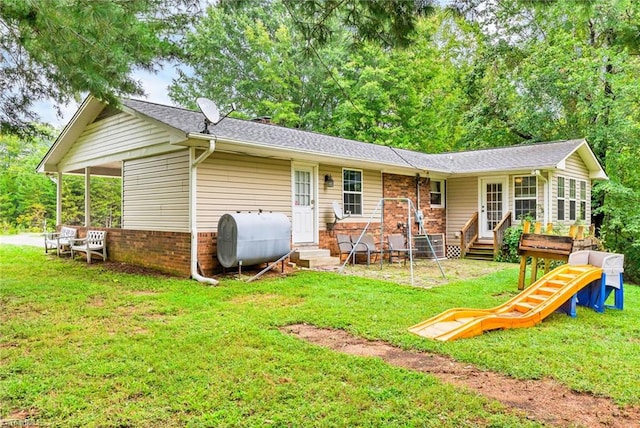 rear view of house featuring a playground and a yard