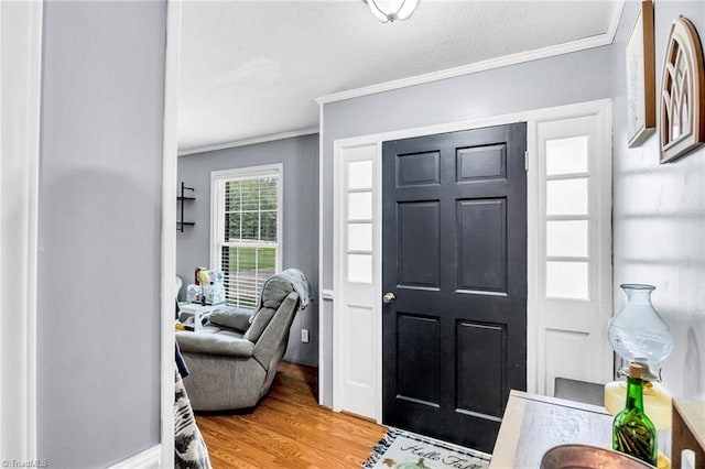 entrance foyer with ornamental molding, wood-type flooring, and a textured ceiling