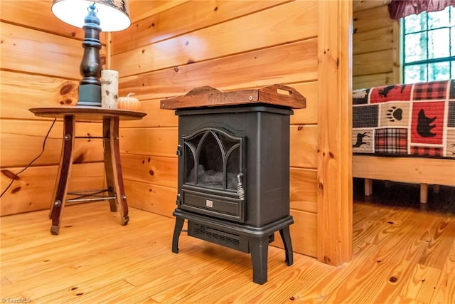 interior details with hardwood / wood-style flooring, a wood stove, and wood walls