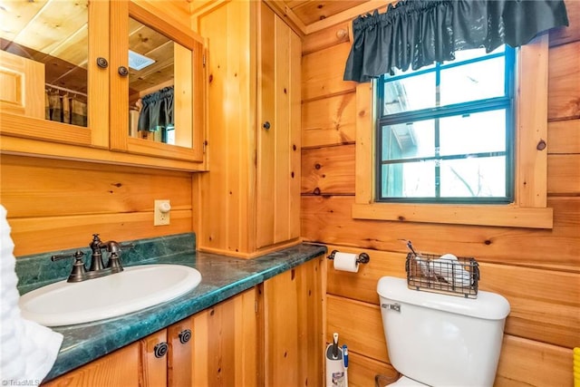 bathroom with vanity, wooden walls, and toilet