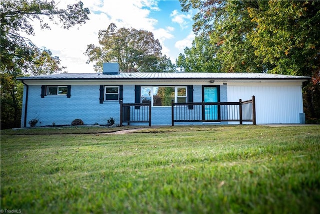 view of front of house with brick siding, a chimney, metal roof, and a front yard