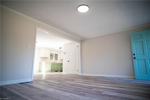 unfurnished living room with visible vents, baseboards, crown molding, and wood finished floors