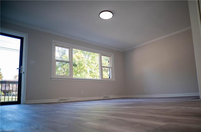 empty room with visible vents, crown molding, and baseboards