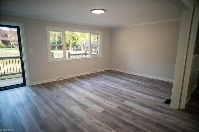 empty room featuring dark wood-style floors, visible vents, baseboards, and crown molding