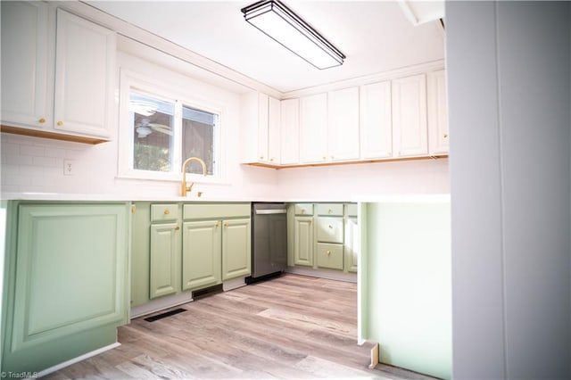 kitchen featuring visible vents, light countertops, light wood-style flooring, green cabinets, and a sink