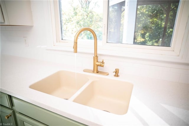 interior details with light countertops, a sink, green cabinetry, and decorative backsplash