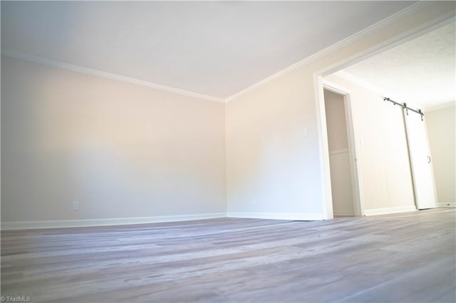 spare room featuring baseboards, wood finished floors, and crown molding