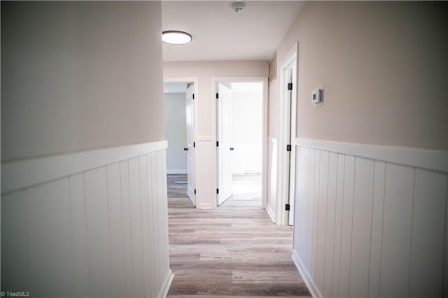 hallway with a wainscoted wall and light wood-style flooring