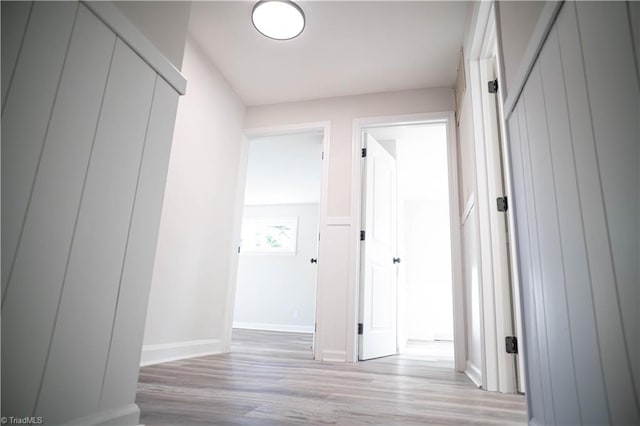 hall with light wood-style floors and baseboards