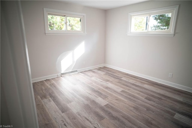 unfurnished room with plenty of natural light, baseboards, and wood finished floors