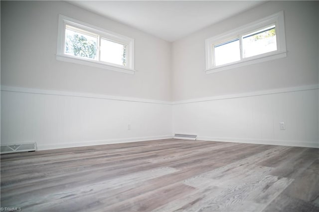 unfurnished room with wainscoting, wood finished floors, and visible vents