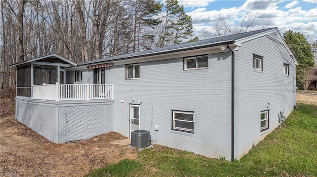 rear view of house featuring central air condition unit, a yard, and brick siding