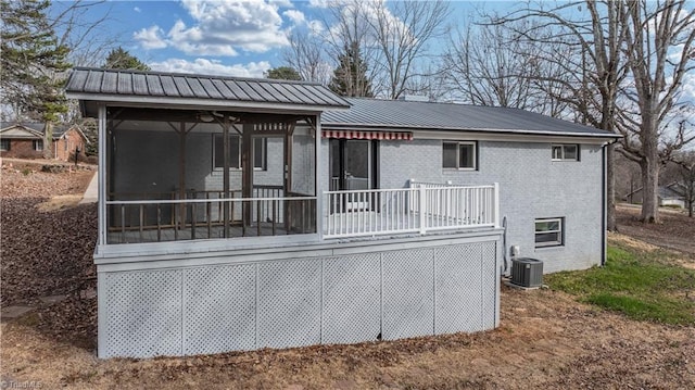 rear view of property with cooling unit, a sunroom, brick siding, and metal roof