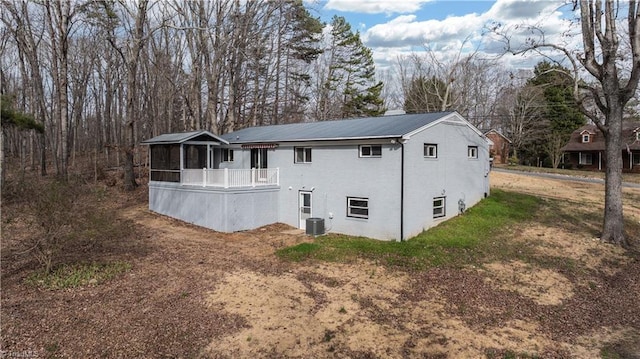 back of property with a sunroom, central AC unit, metal roof, and brick siding