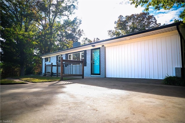 view of front of house featuring concrete driveway, brick siding, and a chimney