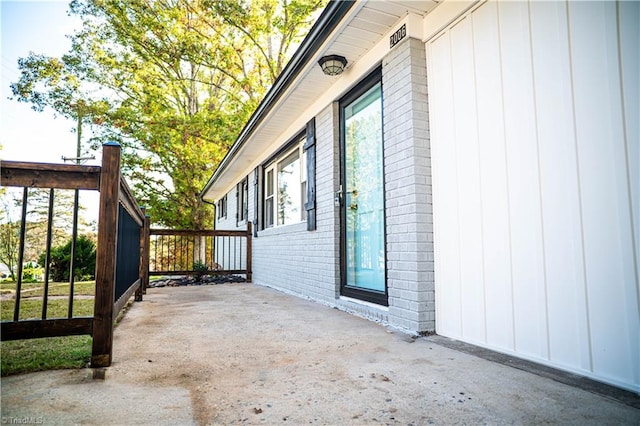 exterior space with board and batten siding, a patio area, and brick siding