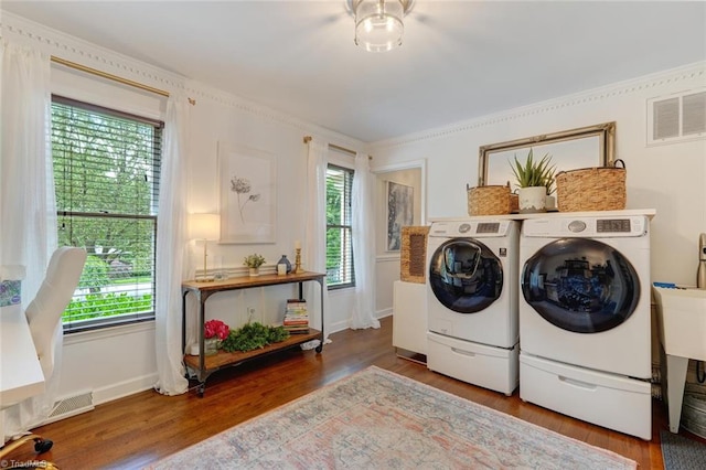 washroom with washing machine and clothes dryer, wood finished floors, healthy amount of natural light, baseboards, and crown molding