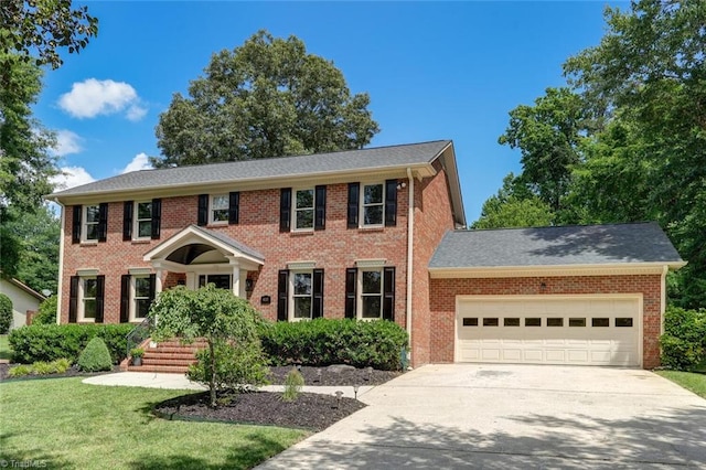 colonial home with an attached garage, driveway, brick siding, and a front yard