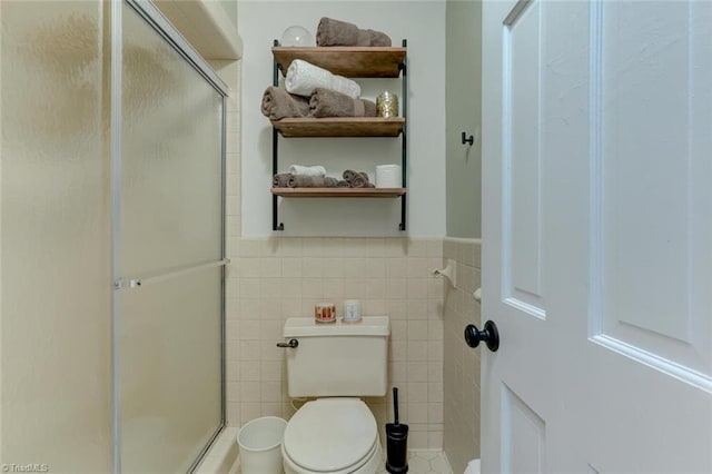 bathroom featuring a stall shower, toilet, tile walls, and wainscoting