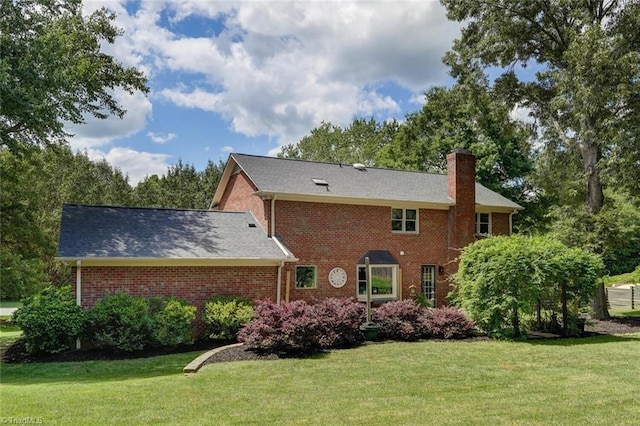 rear view of house with a lawn, a chimney, and brick siding