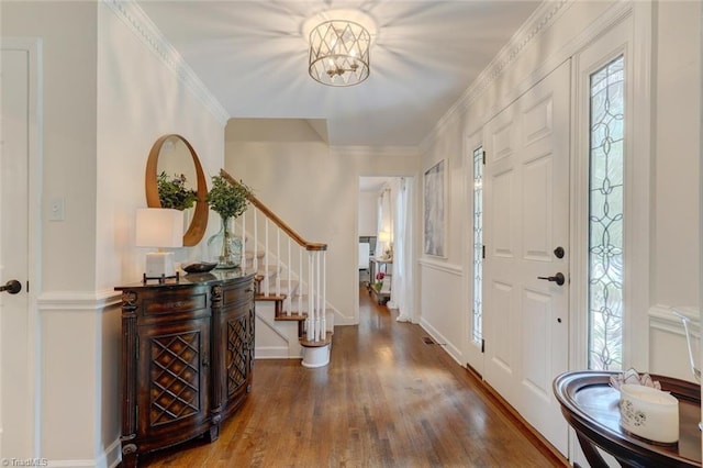 foyer entrance with wood finished floors, stairs, a chandelier, and baseboards