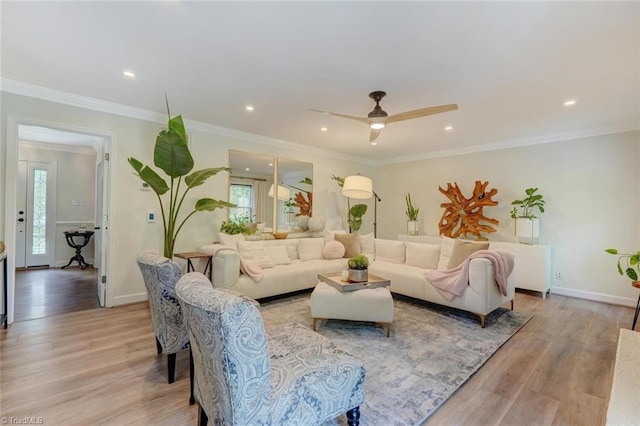 living area featuring plenty of natural light, light wood-style flooring, baseboards, ceiling fan, and crown molding