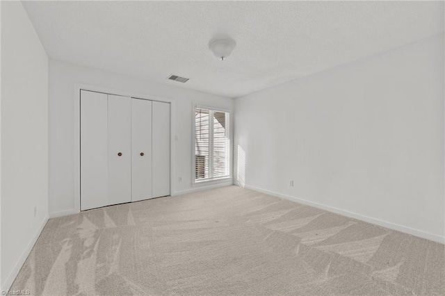 unfurnished bedroom featuring light colored carpet and a closet