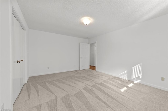 unfurnished room featuring light carpet and a textured ceiling