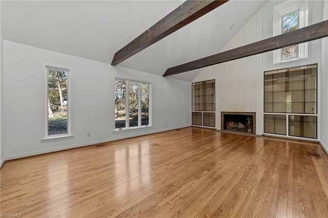 unfurnished living room with a brick fireplace, a wealth of natural light, and light hardwood / wood-style flooring