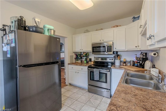 kitchen featuring light tile patterned floors, stainless steel appliances, sink, and white cabinets