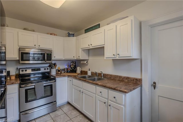 kitchen featuring stainless steel appliances, white cabinetry, sink, and light tile patterned floors