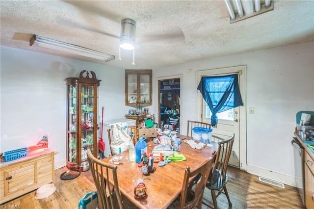 dining area with a textured ceiling and wood finished floors