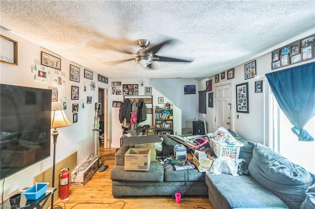 living room featuring wood finished floors, ceiling fan, and a textured ceiling